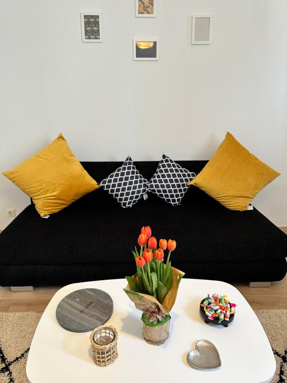 een zwarte bank met gele kussens en een tafel met bloemen bij Cozy 8-Person Home in Vienna Located at Haberlgasse 82 N1 in Wenen