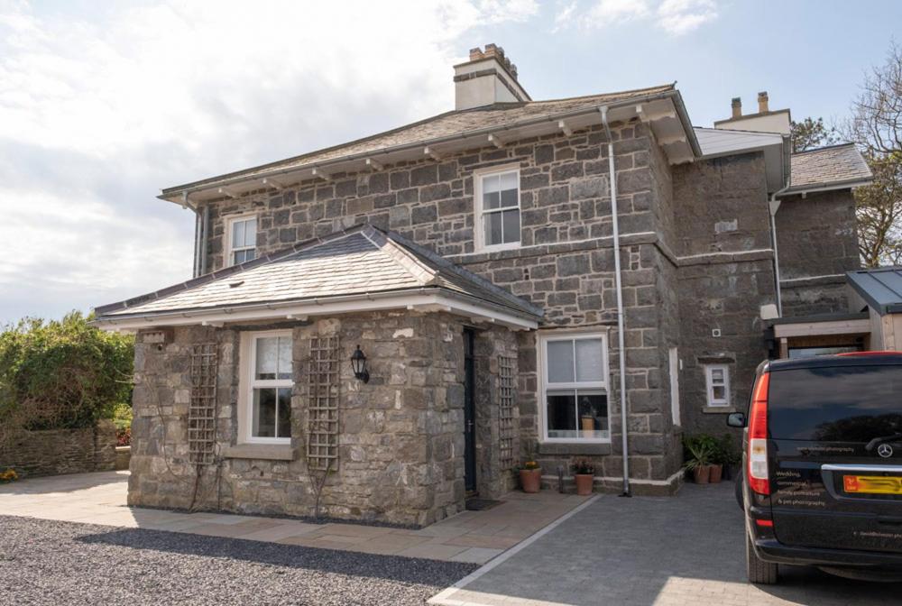 une maison en pierre avec une voiture garée devant elle dans l'établissement Church Farmhouse - Castle View (4 bedroom) & Church View (2 bedroom), à Castletown