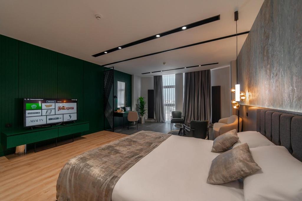 una camera con un grande letto e una TV a schermo piatto di Dostyk Business Hotel ad Aqtau