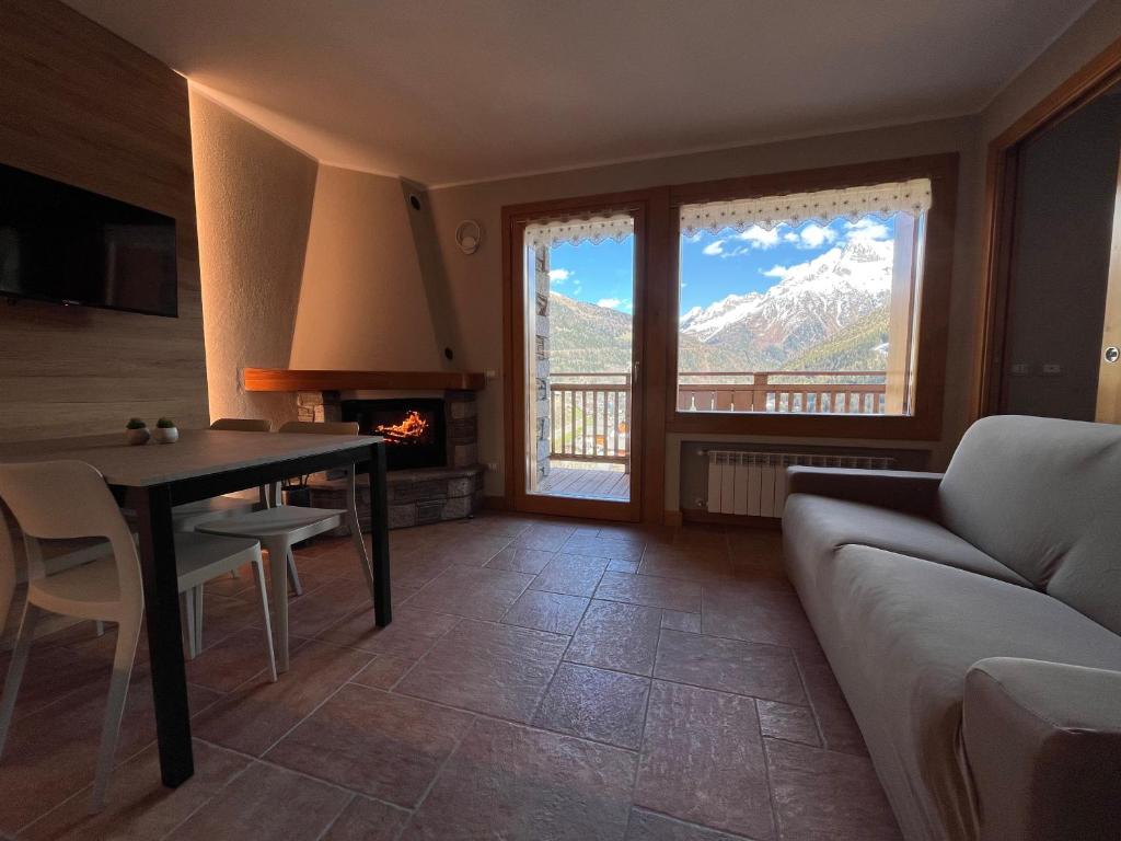 un soggiorno con divano, tavolo e camino di Chalet La Stella Alpina a Villa dʼAllegno