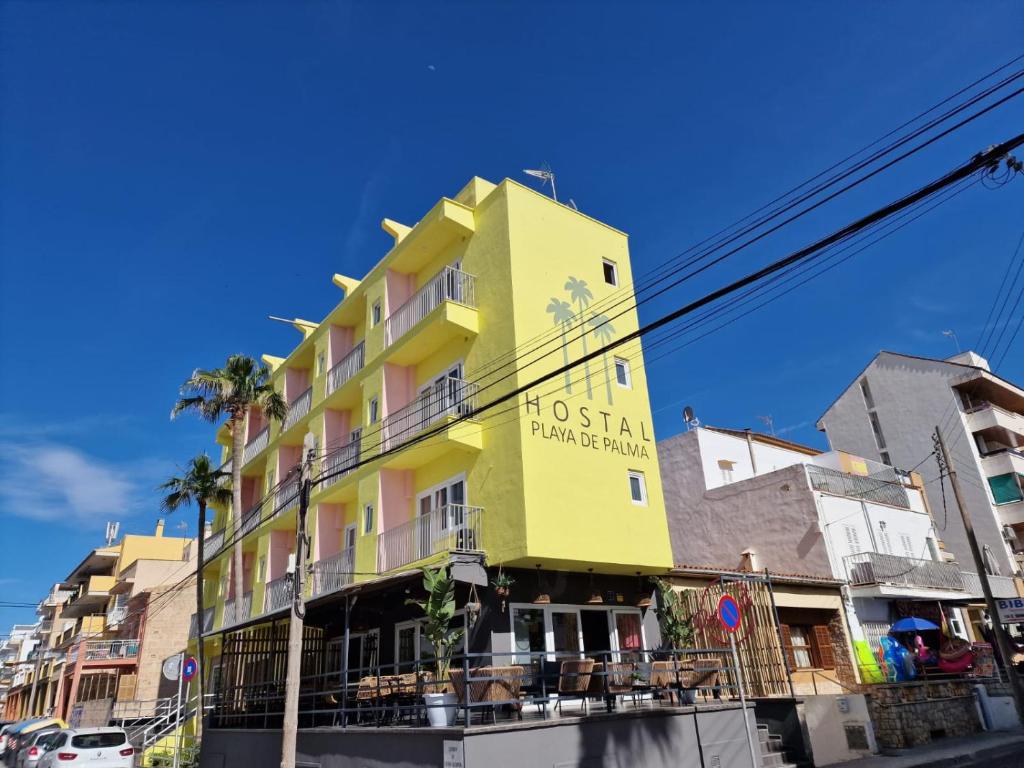 un bâtiment jaune avec un hôtel sur son côté dans l'établissement Hostal Playa de Palma, à Playa de Palma