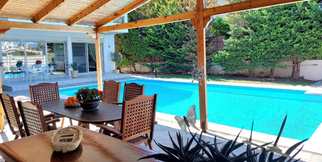 een patio met een tafel en stoelen en een zwembad bij Luxury apartment SEA HELM with private swimming pool and BBQ in Lagonissi