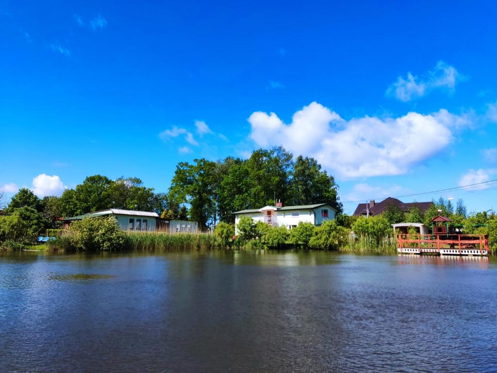 a group of houses on the shore of a lake at Agroturystyka Wypoczynkowa II in Zieleniewo