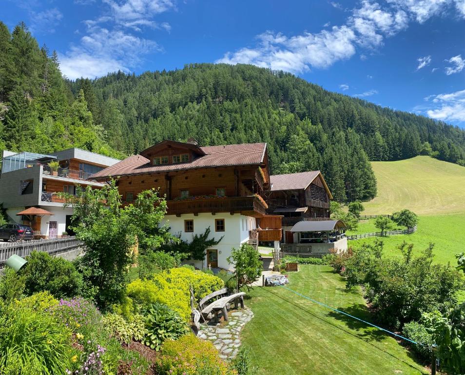 a house in the mountains with a field and trees at Ruggenthalerhof in Matrei in Osttirol