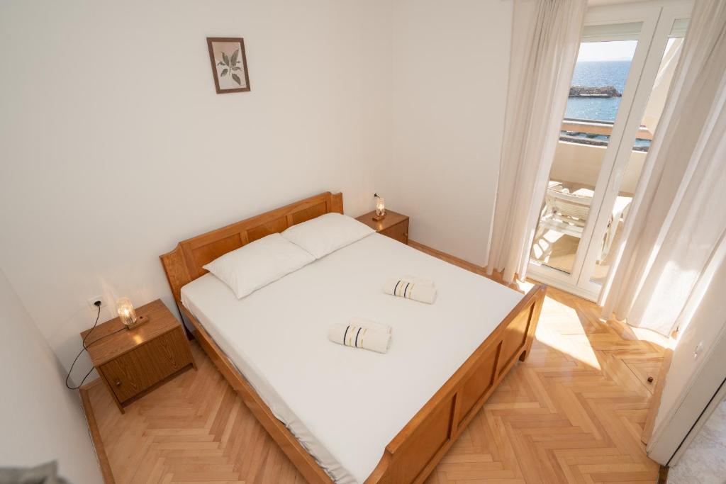 a bedroom with a white bed and a large window at Apartments and rooms LJUBICA in Lun
