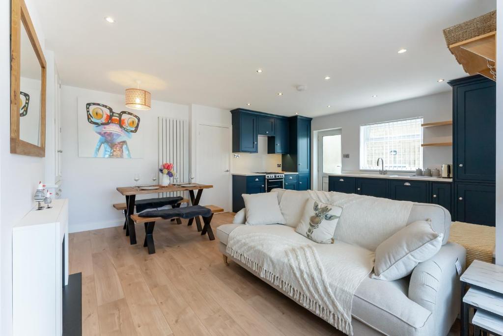 a living room with a white couch and a kitchen at Quiet Cotswold Bungalow in Charlbury