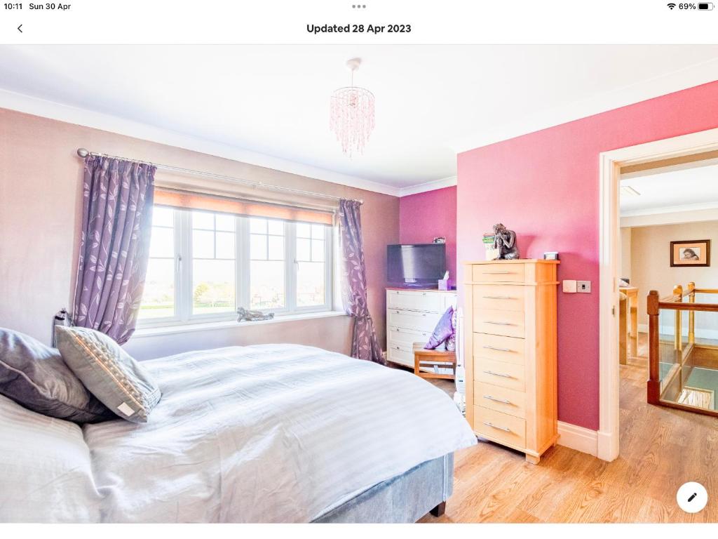 a bedroom with pink walls and a bed and a window at King's Suite at The Copthorne, Colwyn Bay, LL29 7YP in Colwyn Bay