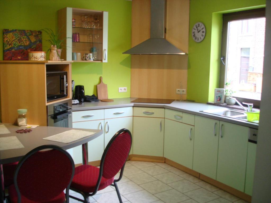 a kitchen with green walls and a table and chairs at appartement Courcelles in Courcelles