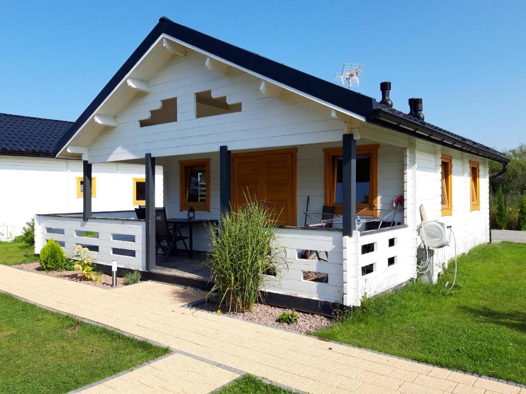 a white house with a porch and a lawn at Baltic-Star in Gąski