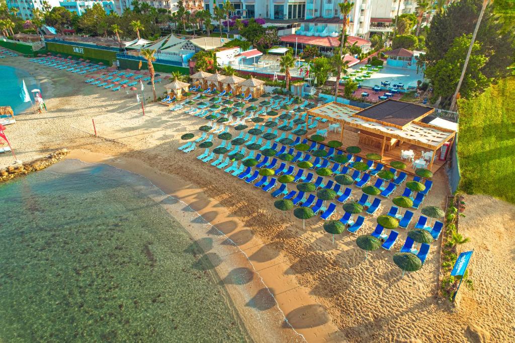 Ramira Beach Hotel - All Inclusive في أفسالار: اطلالة علوية على شاطئ به مظلات زرقاء