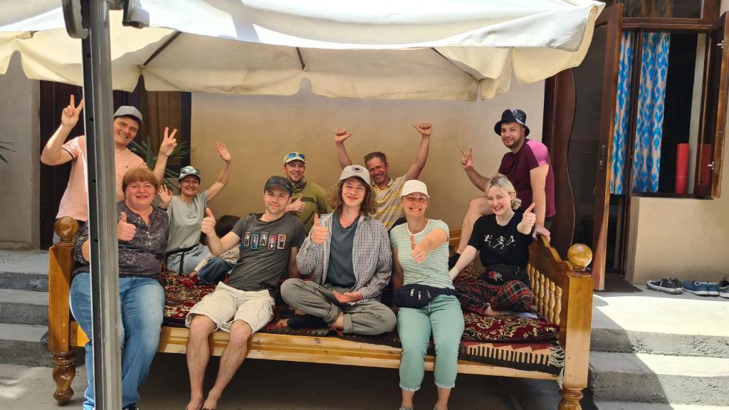 a group of people sitting on a bed at Azaliya Hostel in Samarkand