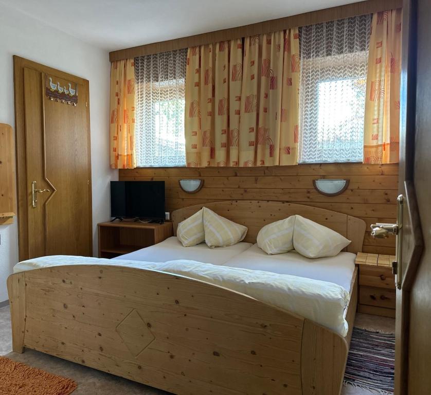 a bedroom with a large wooden bed with windows at Haus Luxer in Auffach