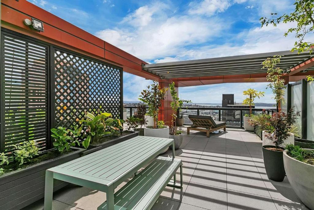 a patio with a bench and plants on a balcony at City and view holiday home in Auckland