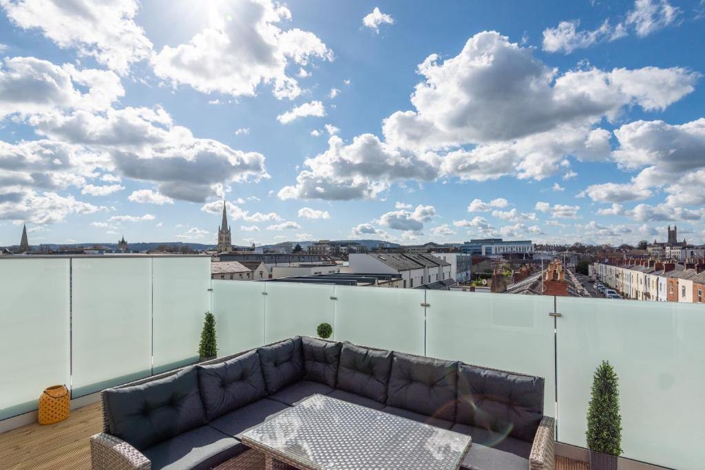 einen Balkon mit einem Sofa und Stadtblick in der Unterkunft The Burton Penthouse in Cheltenham