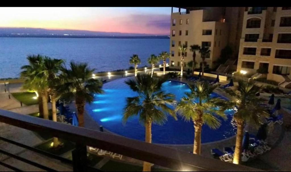 un balcón con vistas a una piscina con palmeras en Dead Sea view Elite apartment Samara Resort traveler award 2024, en Sowayma