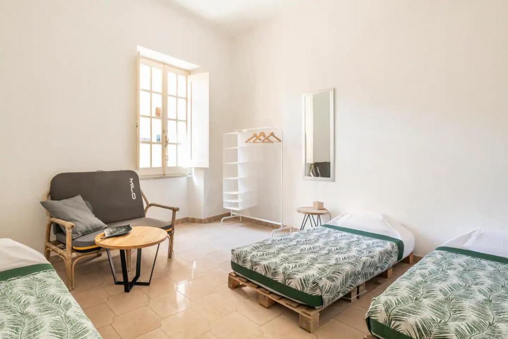 Habitación con 2 camas, silla y mesa. en Safeheaven Sardinia en Dorgali