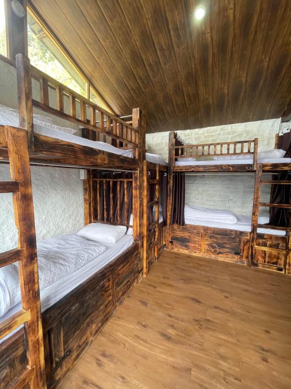 a room with three bunk beds in a cabin at Parvatis Lap Luxury Hostel & Camps in Kasol