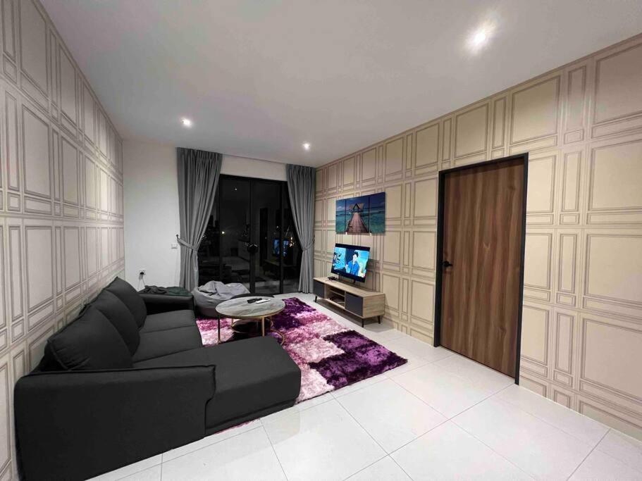 een woonkamer met een zwarte bank en een tv bij Armadale Residence Galacity 3 bedroom in Kampong Tabuan
