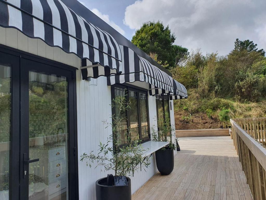 a building with a black and white awning on it at Tiny house with greenhouse dining in Lower Hutt