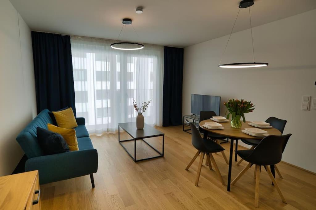 sala de estar con mesa y sofá azul en Modern apartment near Stadtpark en Viena