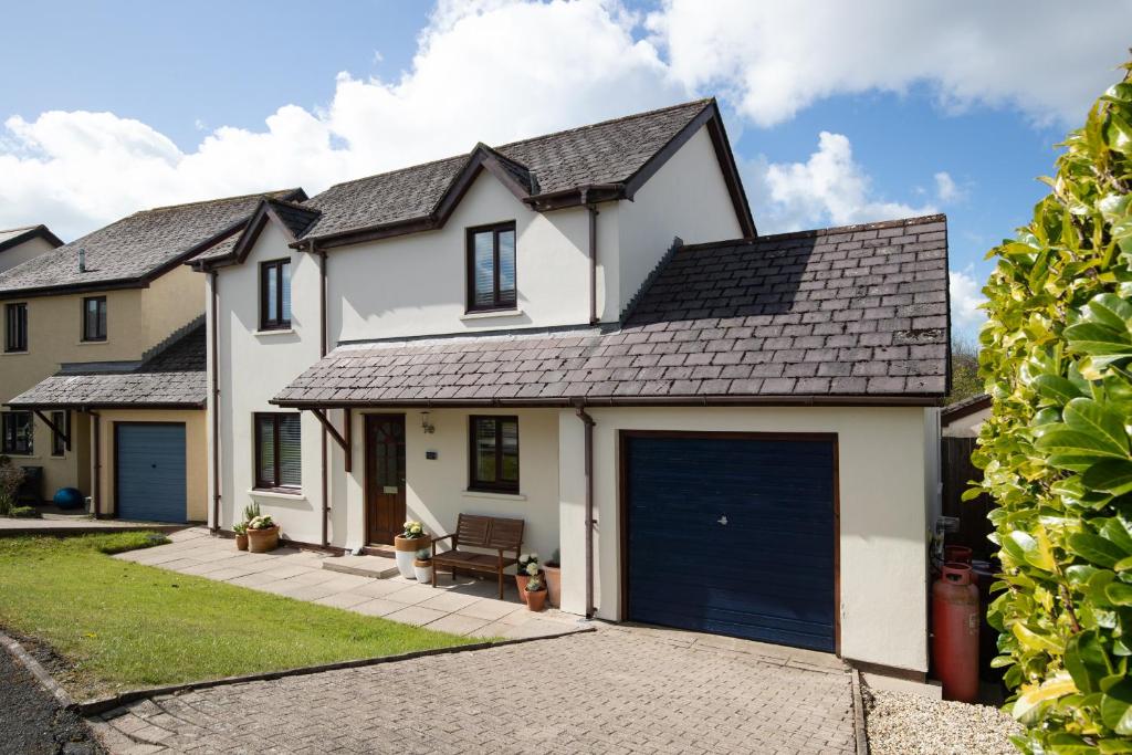 a white house with a blue garage at Woodfield House - Beautiful Tenby Cottage in Tenby