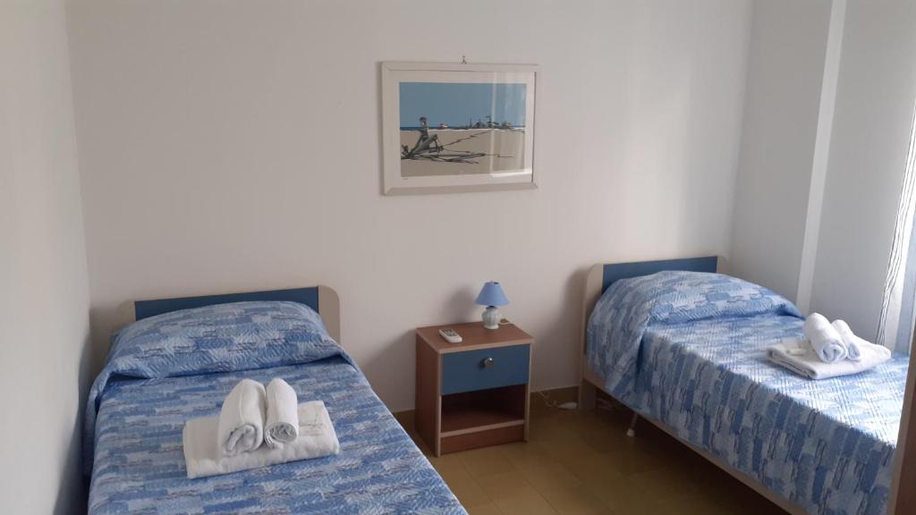 two beds in a room with towels and shoes on them at Central Station House in Santa Marinella