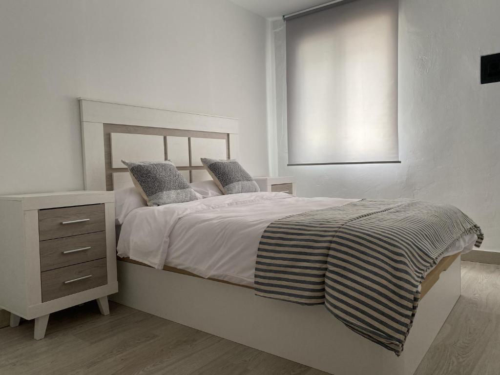 a white bedroom with a bed and a night stand at Apartamento Suite Córdoba in Córdoba