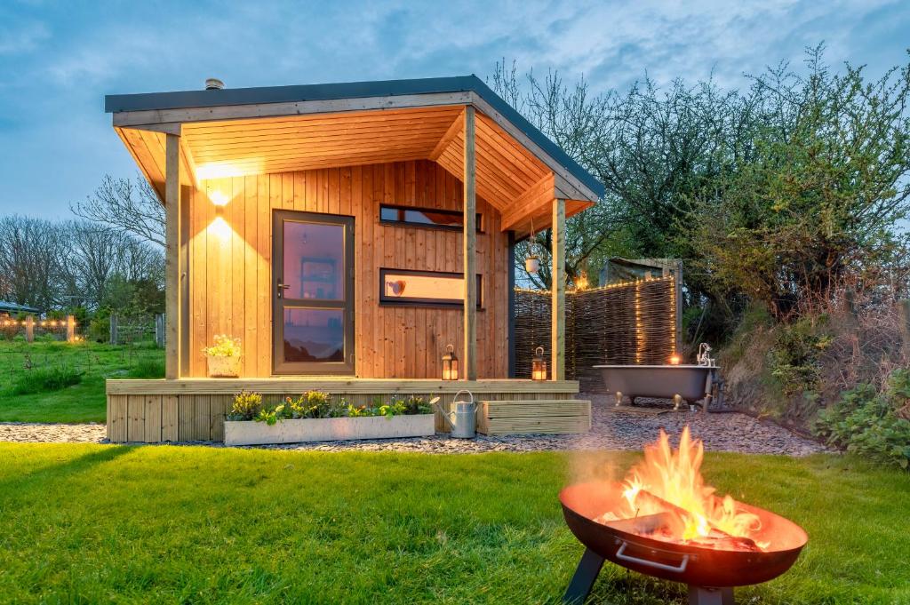 a tiny house with a fire pit in the yard at Luxury Glamping Cabin with Outdoor Bath on Cornish Flower Farm in Truro