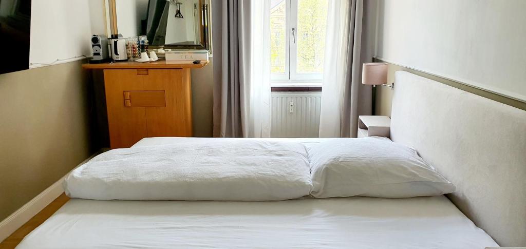 a white bed in a room with a window at gemütliches Privatzimmer in Mannheims Stadtmitte in Mannheim