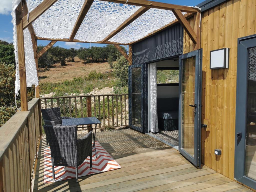 une terrasse en bois avec une pergola et une table dans l'établissement Camping les lodges du lagon, à Calvisson