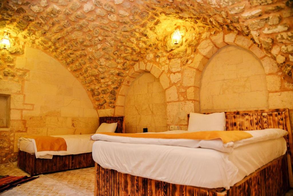 karagül otel في سانليورفا: غرفة نوم بسريرين في غرفة حجرية