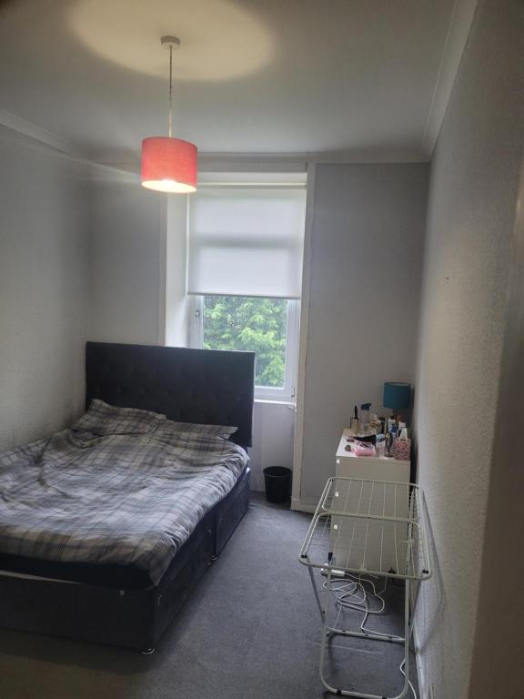 um pequeno quarto com uma cama e uma janela em Tollcross Near Glasgow City Centre em Glasgow