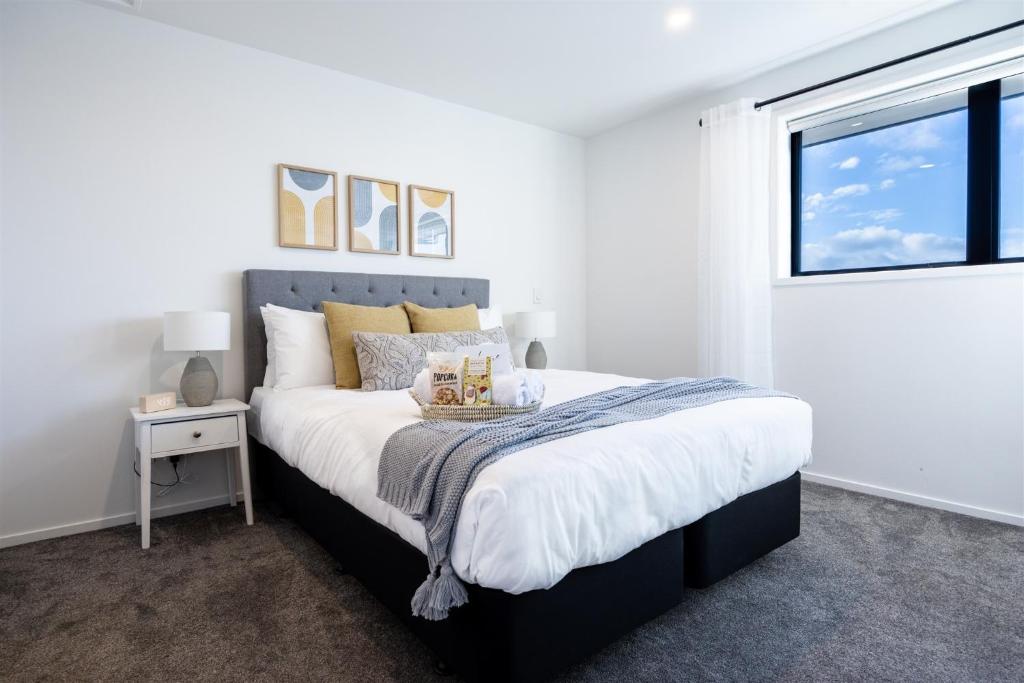 a white bedroom with a large bed with a window at Stylish home in Christchurch central in Christchurch