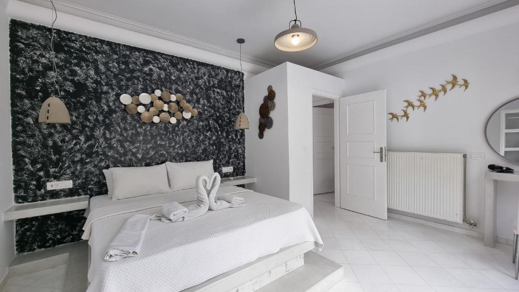 a bedroom with a white bed and a black and white wall at 3 Bedroom House included free car rental in Perissa