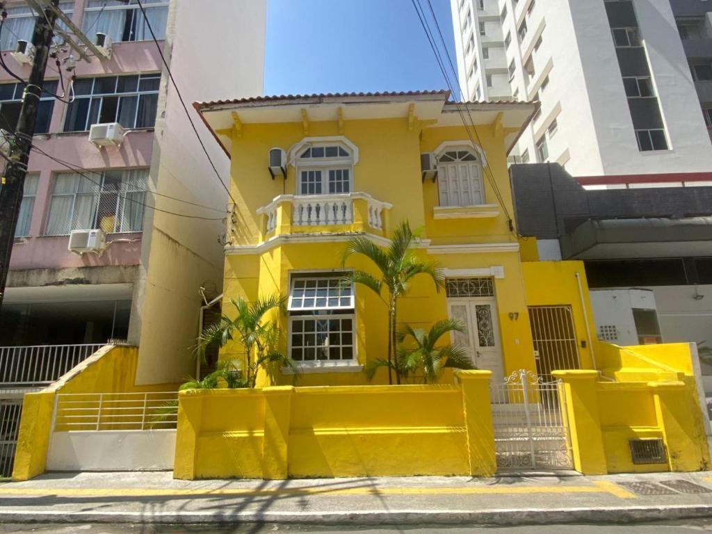 a yellow house with palm trees in front of it at Sunflower Hostel in Salvador