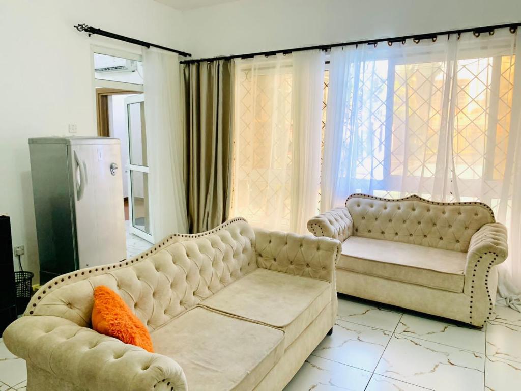 a living room with two couches and an orange pillow at Lux Suites 1 Bedroom Hydro Apartments Nyali in Mombasa