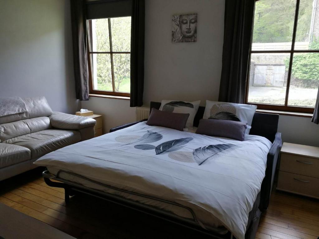 uma cama grande num quarto com um sofá em La sittelle des aguesses em Andenne