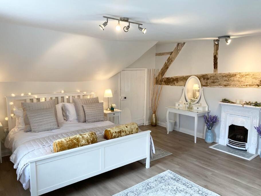 Boothorpe Farmhouse في Blackfordby: غرفة نوم بيضاء مع سرير أبيض ومدفأة