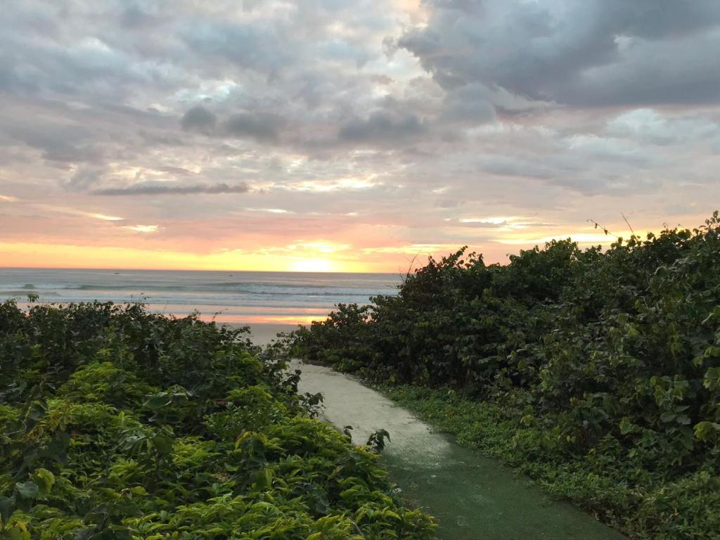 un sentiero sporco che conduce a una spiaggia con un tramonto di Linda Casa frente mar, pé na areia, Itapema SC, Ar, Wi-fi, Smart Tv a Itapema