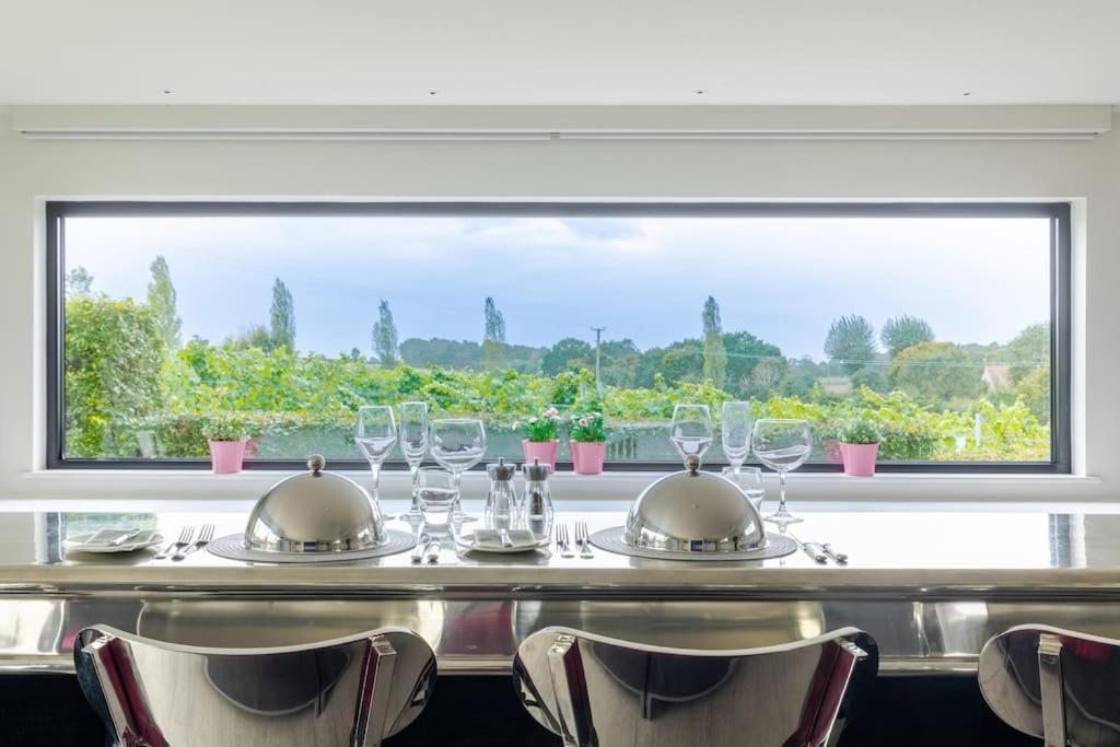 Toppesfield的住宿－Toppesfield Vineyard luxury, contemporary villa - 2 adults，一张带酒杯的桌子和大窗户