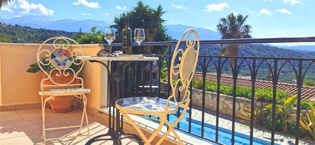 GavalochoriにあるVilla Koumos - Crete Holidays With Pool and Viewsのバルコニー(椅子2脚、テーブル、ワイングラス付)
