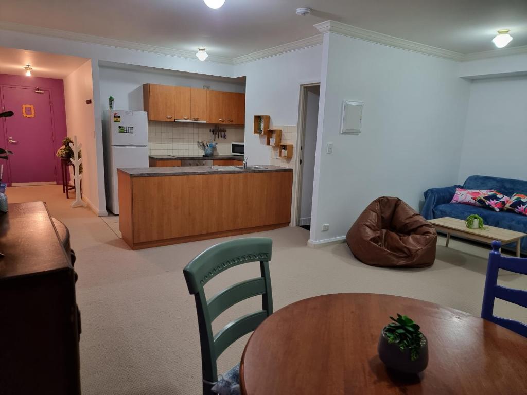 a living room with a table and a kitchen at Little Monica Apartment- Spacious, Affordable & Central in Perth