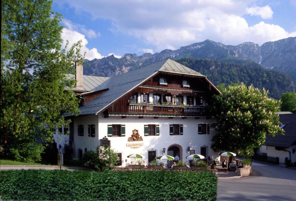 Un grand bâtiment blanc avec des montagnes en arrière-plan dans l'établissement "Kaiser Karl" *** Ferienwohnungen, à Großgmain