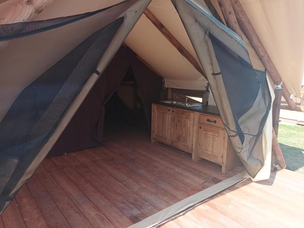 Tienda con suelo de madera y mesa. en Tente Lodge pour 5 personnes en bordure de la rivière Allier, en Saint-Yorre