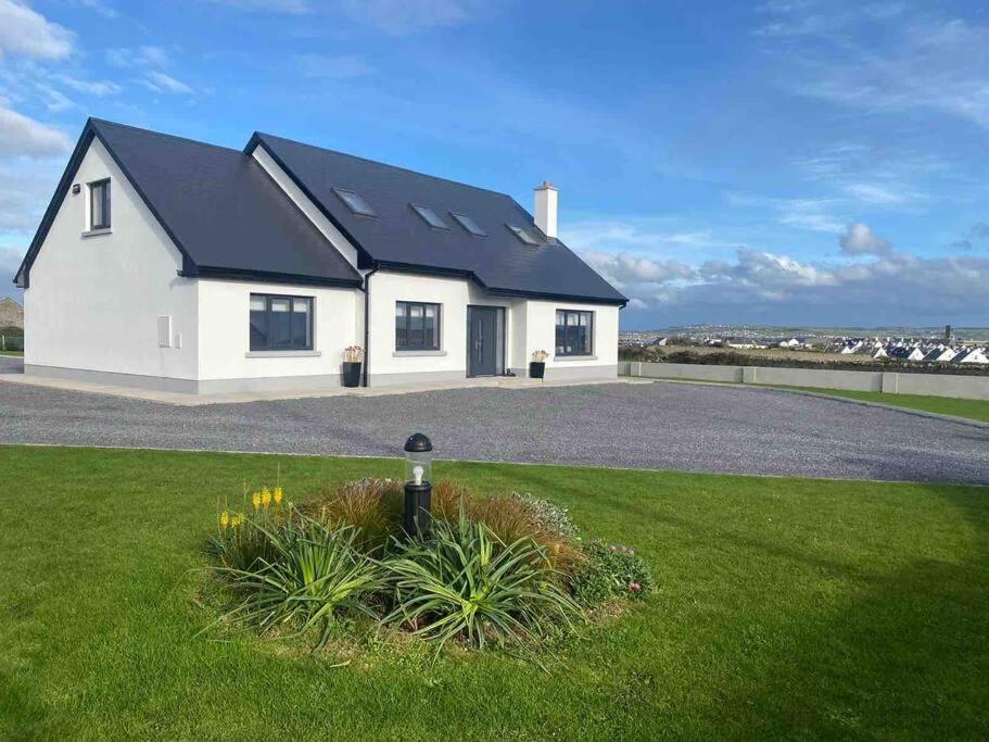 a white house with a black roof at Castle View Rooms in Liscannor