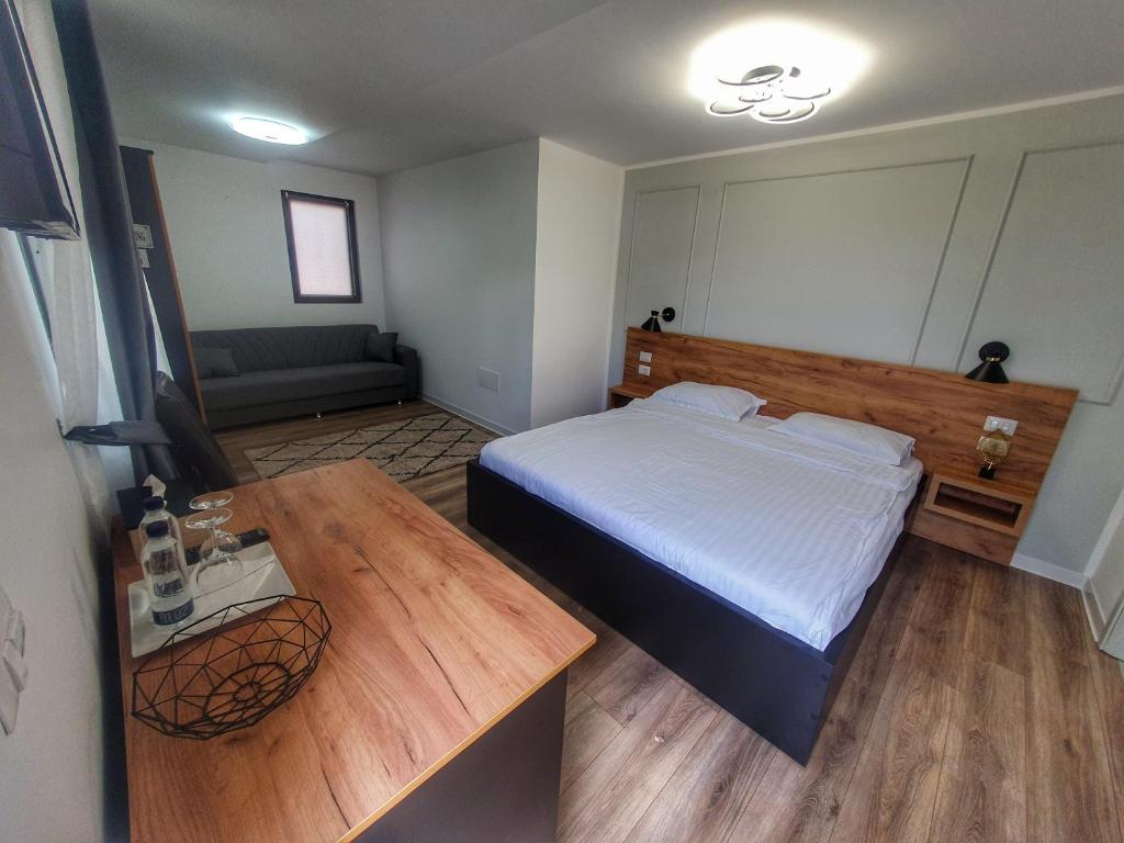 een slaapkamer met een bed en een houten tafel bij Vily Luxury Rooms in Focşani