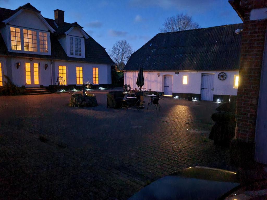 a house with lights on in a courtyard at night at Trandafir Guesthouse in Egtved