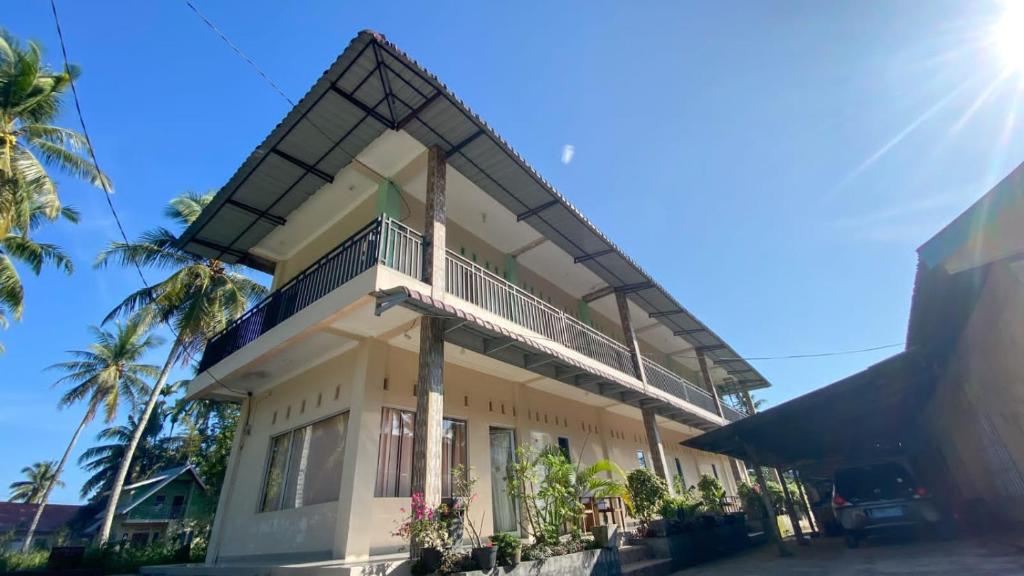 un edificio con balcón y palmeras en Penginapan Malompek Syariah en Duku