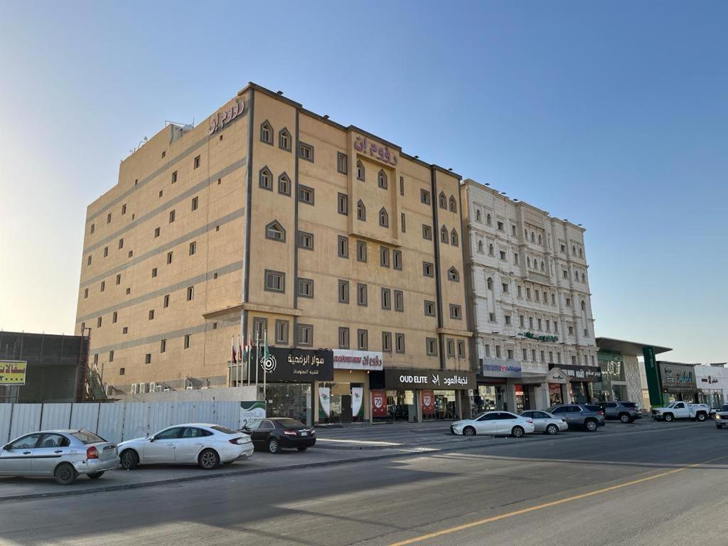 ein großes Gebäude in einer Stadtstraße mit parkenden Autos in der Unterkunft Raoum Inn Hafr Al Baten in Hafar Al-Batin