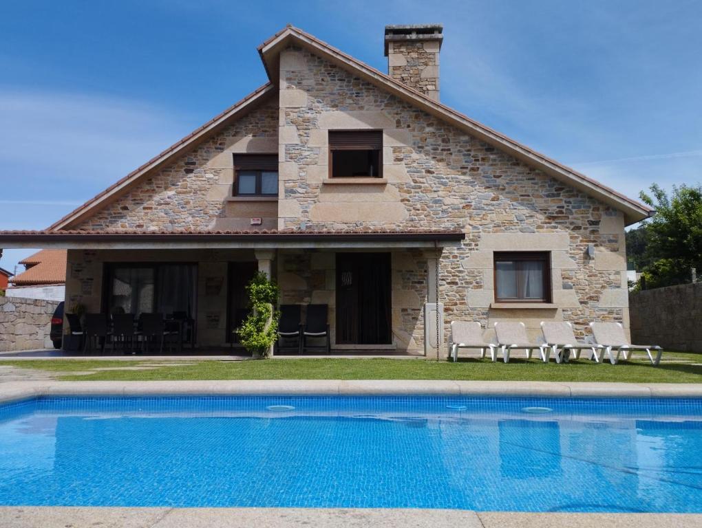 uma villa com piscina em frente a uma casa em VILLA A CANLE em Catoira